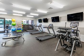 A gym with treadmills and other exercise equipment and televisions